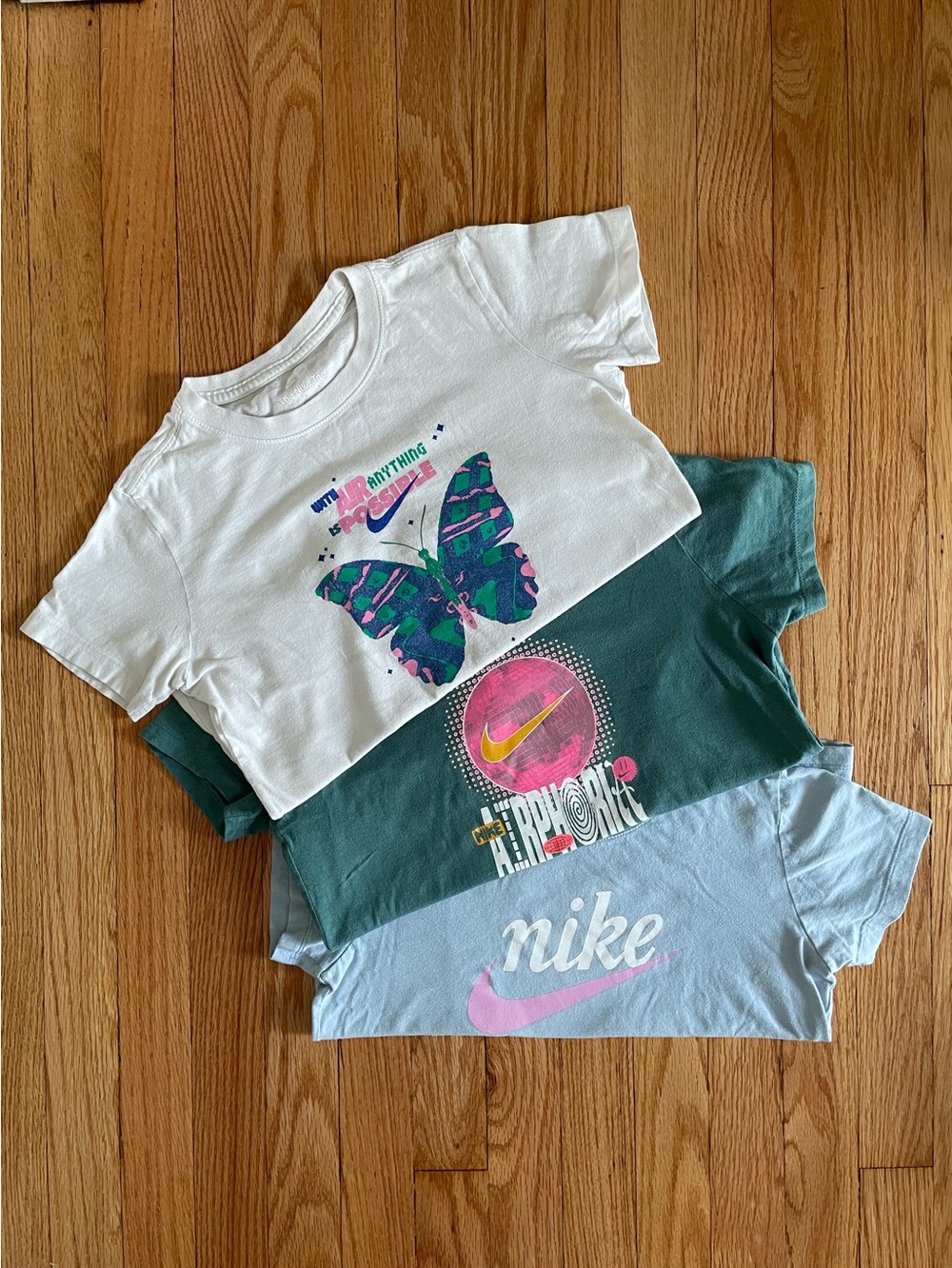 Three Nike graphic T-shirts, all in Kids Size M. White, Green, Light Blue